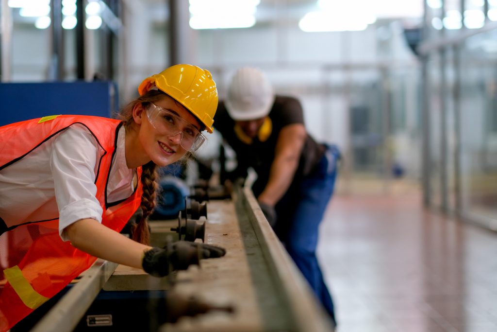 Manufacturing apprentice learning trade skills from experienced colleaguess